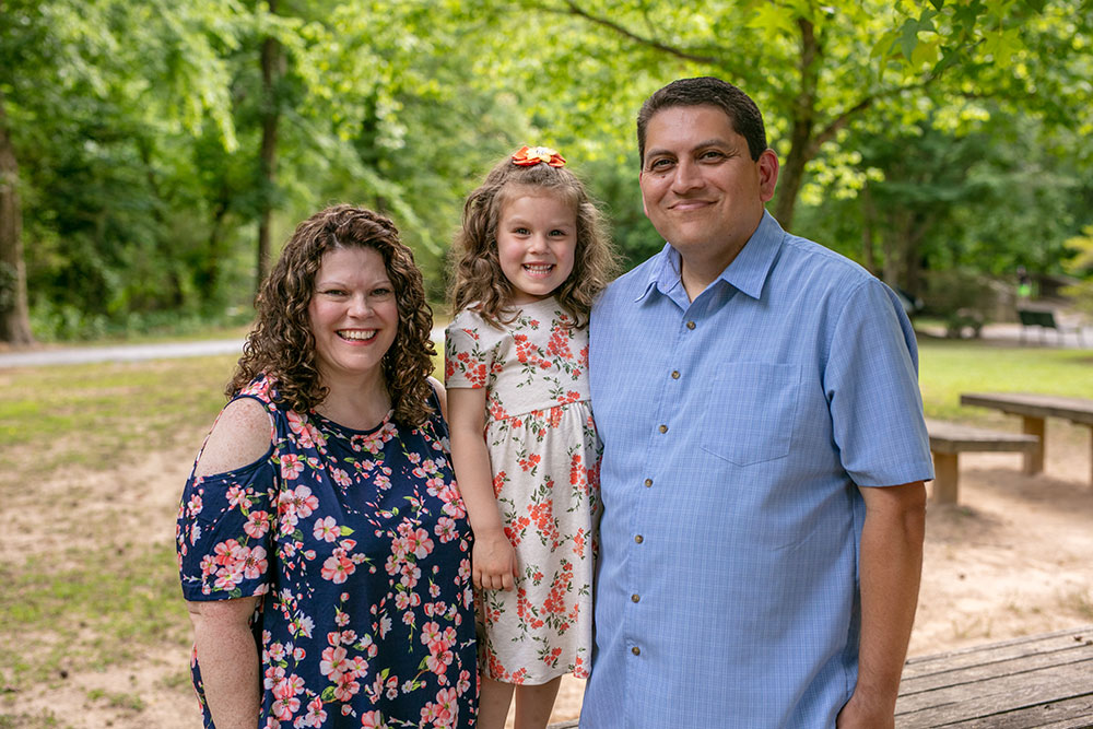 Micheal with his daughter and wife standing in front of a park setting in East Cobb