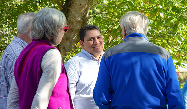 Image of Micheal speaking with three community members with their backs turned to the camera in an outdoor environment